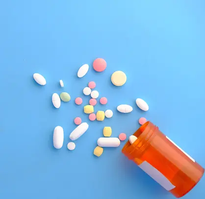 Open pill bottle, with pills spilled on a surface.